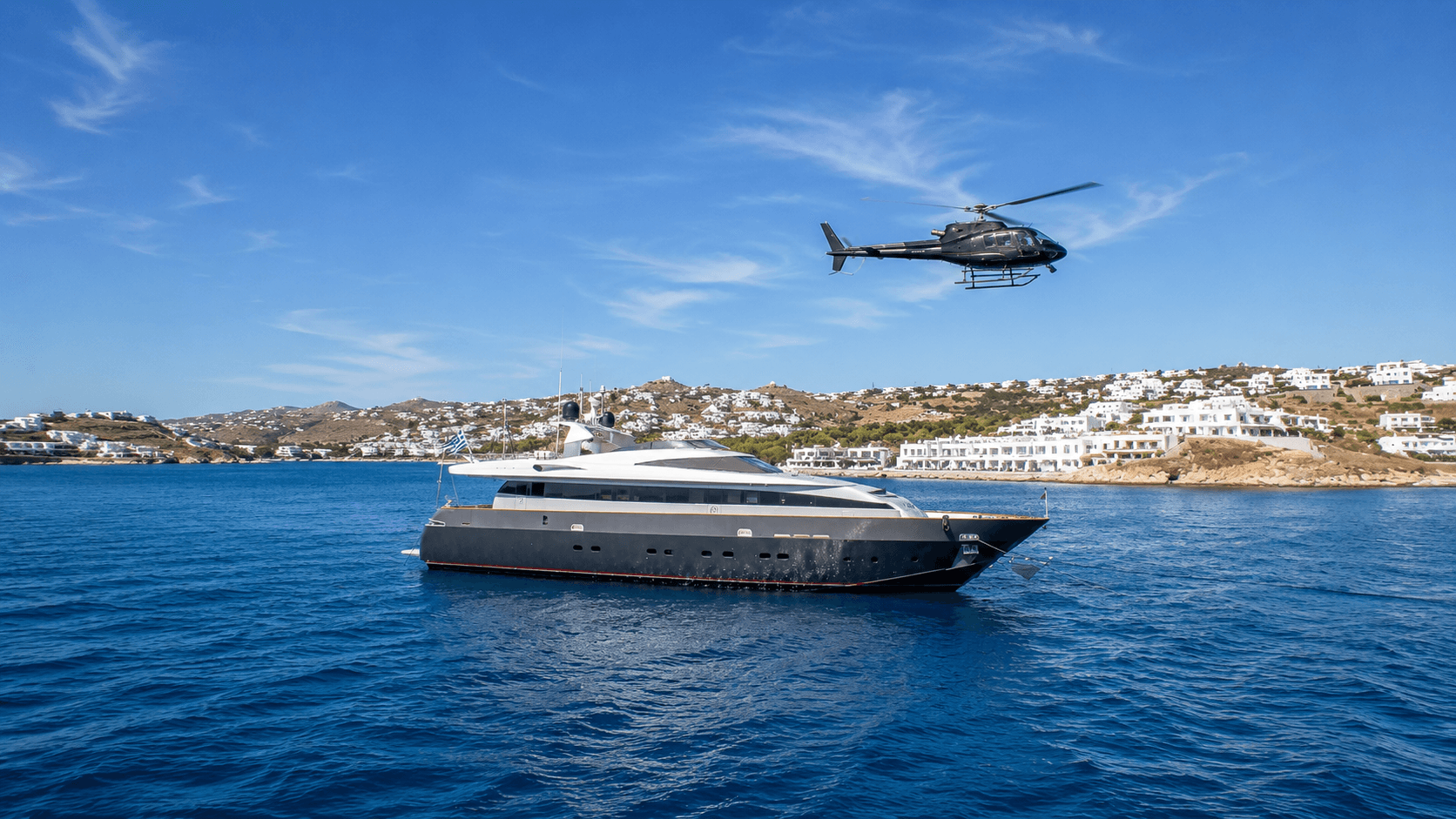 Helicopter arriving alongside a luxury motor yacht anchored off Mykonos